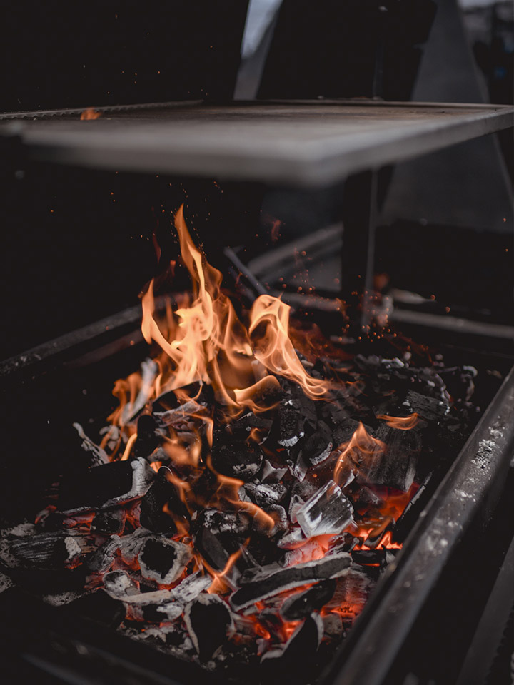 Brasero de Marché Noir : braise et flammes sous la plaque, avant le service