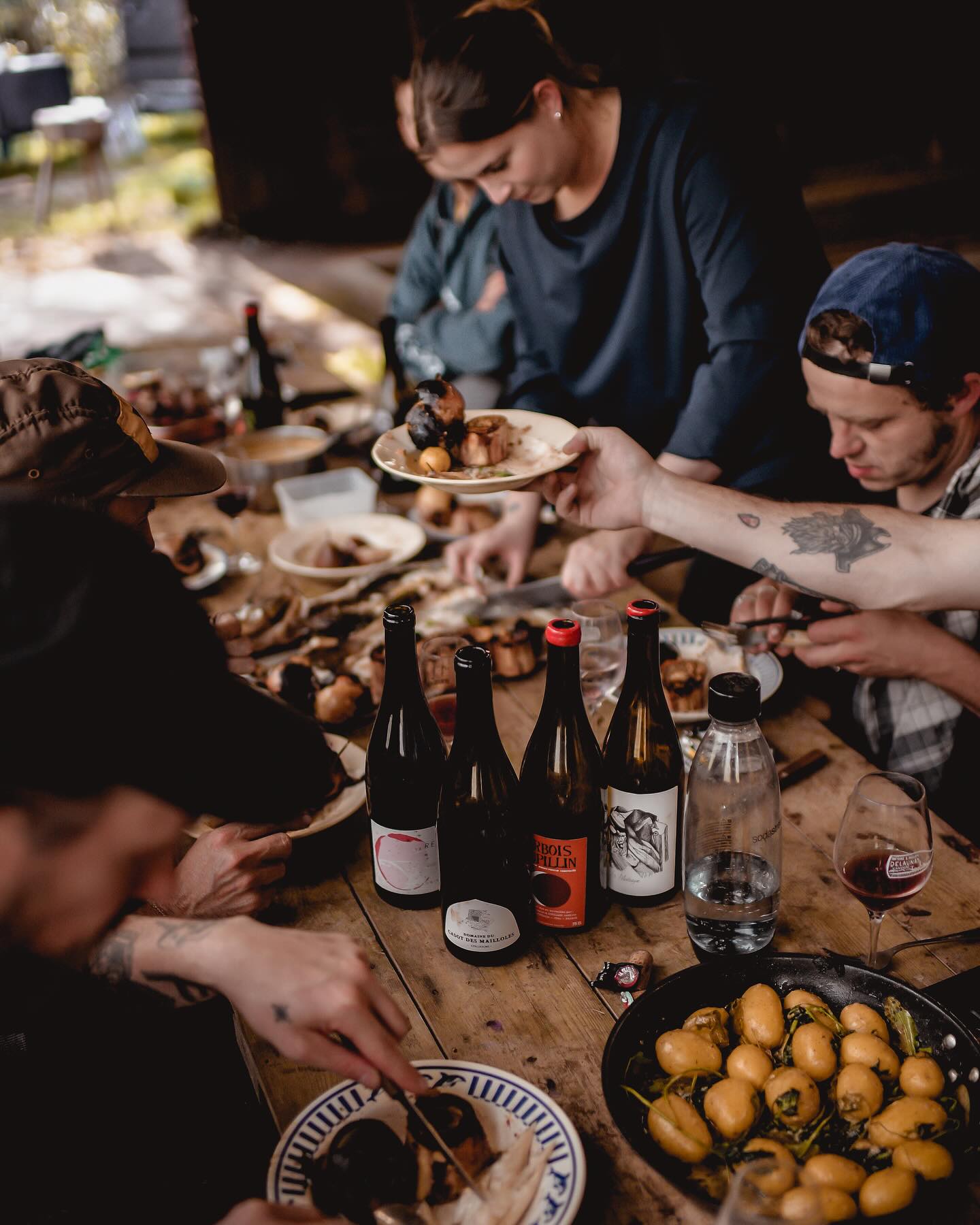 Invités partageant les plats et le vin autour d'une grande table